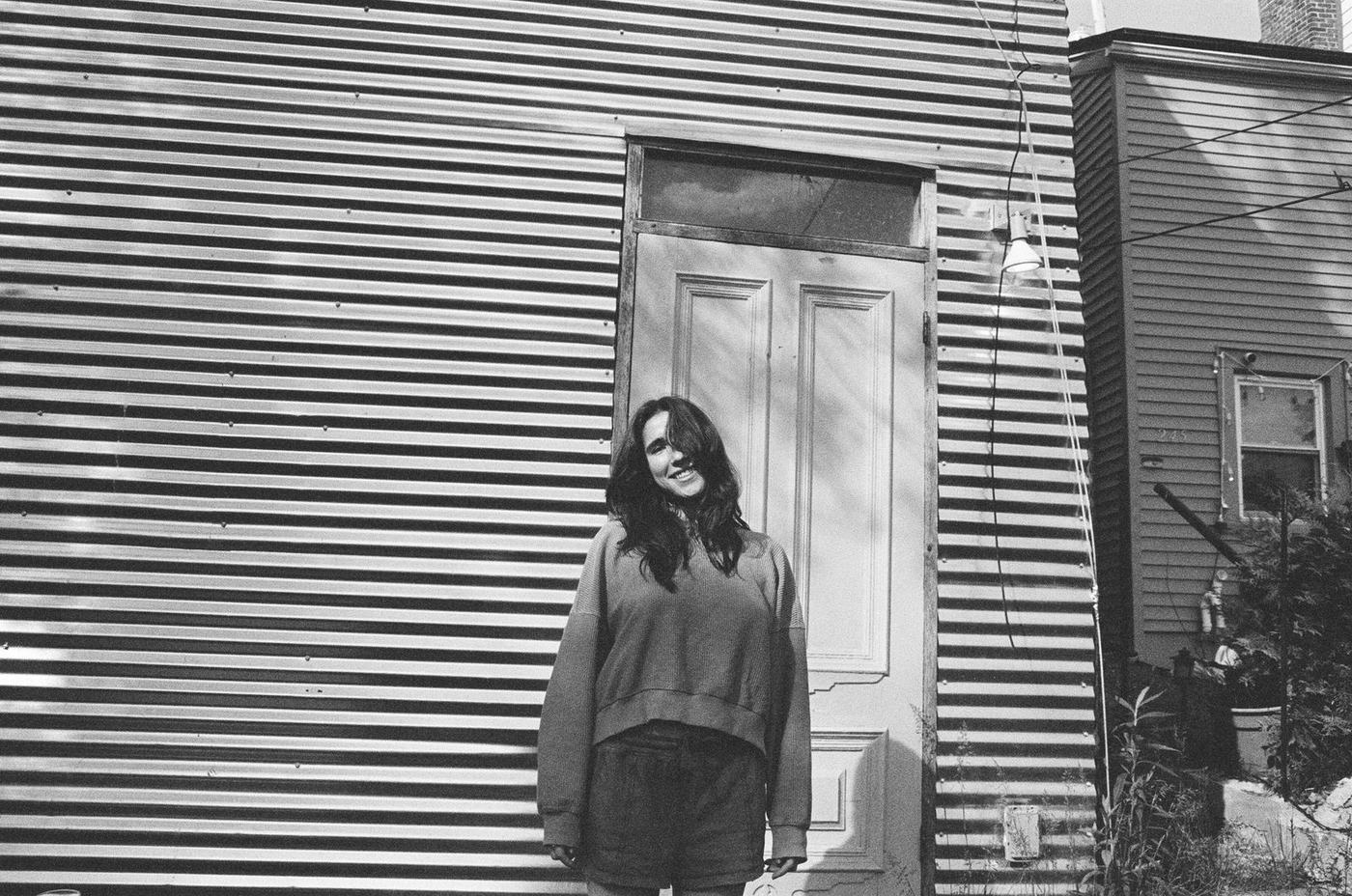 Woman with eyes closed in front of a corrugated metal wall